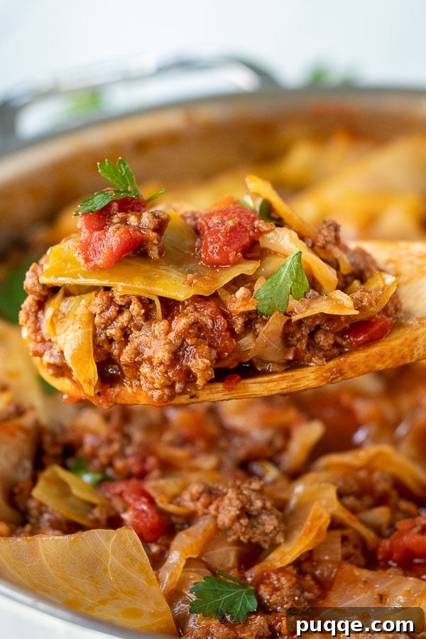 A wooden spoon lifting a spoonful of rich, savory unstuffed cabbage rolls mixture, showcasing the tender beef and cabbage.