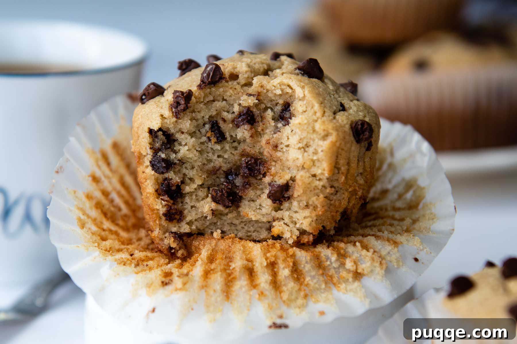 A close-up shot of an almond flour chocolate chip muffin with a bite taken out, showcasing its fluffy interior and melty chocolate chips.