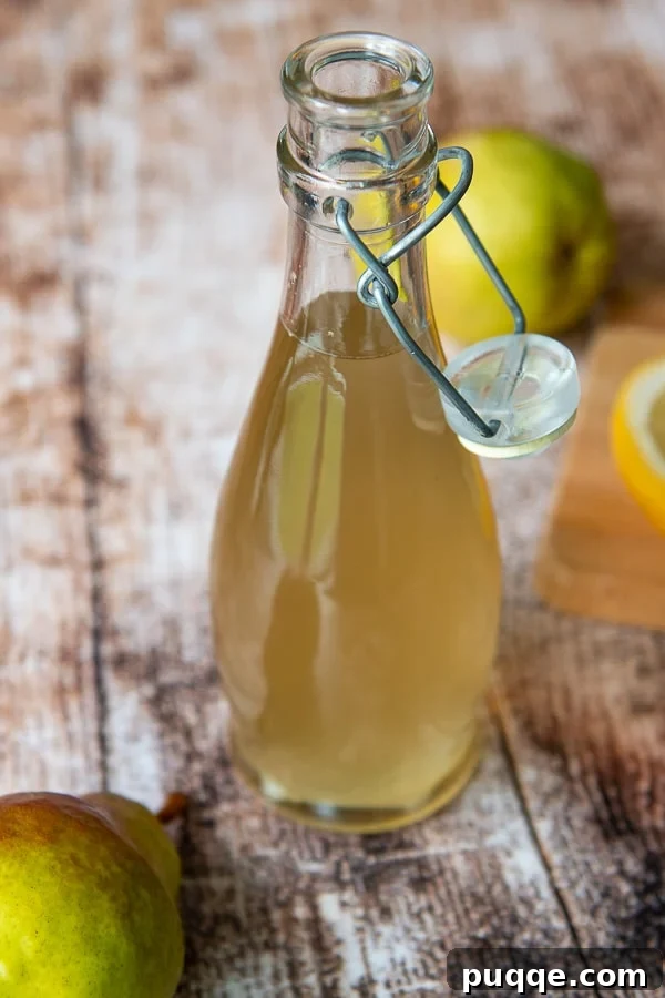Crafting Perfect Fresh Ginger Simple Syrup 2 A bottle of golden ginger simple syrup next to a fresh pear, highlighting its natural goodness.
