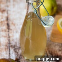 Crafting Perfect Fresh Ginger Simple Syrup 5 A bottle of ginger simple syrup in a glass bottle with a fresh pear next to it