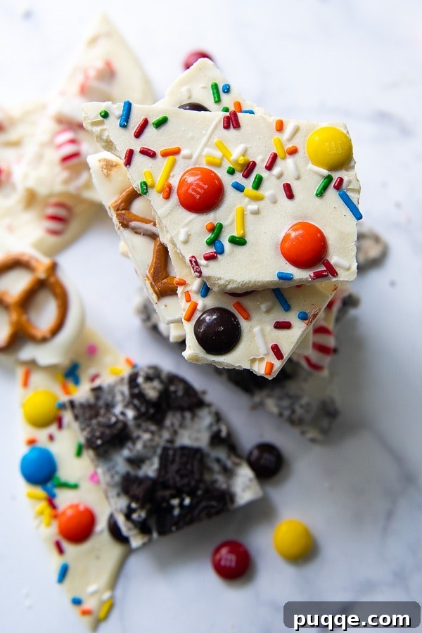 An overhead view capturing the vibrant array of homemade white chocolate barks, featuring variations like Oreo, peppermint, pretzel, and colorful Christmas bark, arranged attractively.