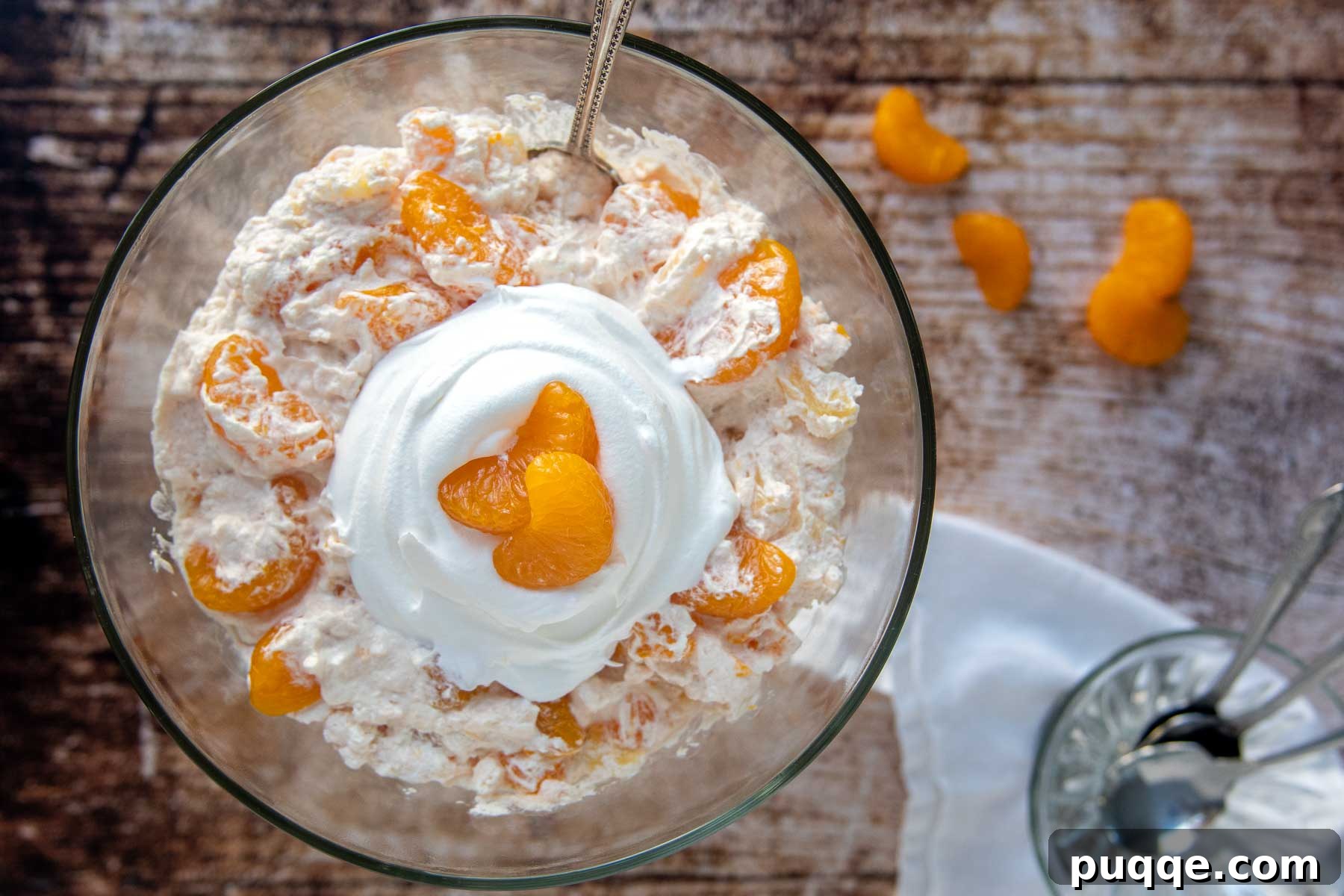 Mandarin Orange Cloud Delight 7 An inviting overhead shot of orange jello salad in a large, elegant glass serving bowl, ready to be enjoyed.