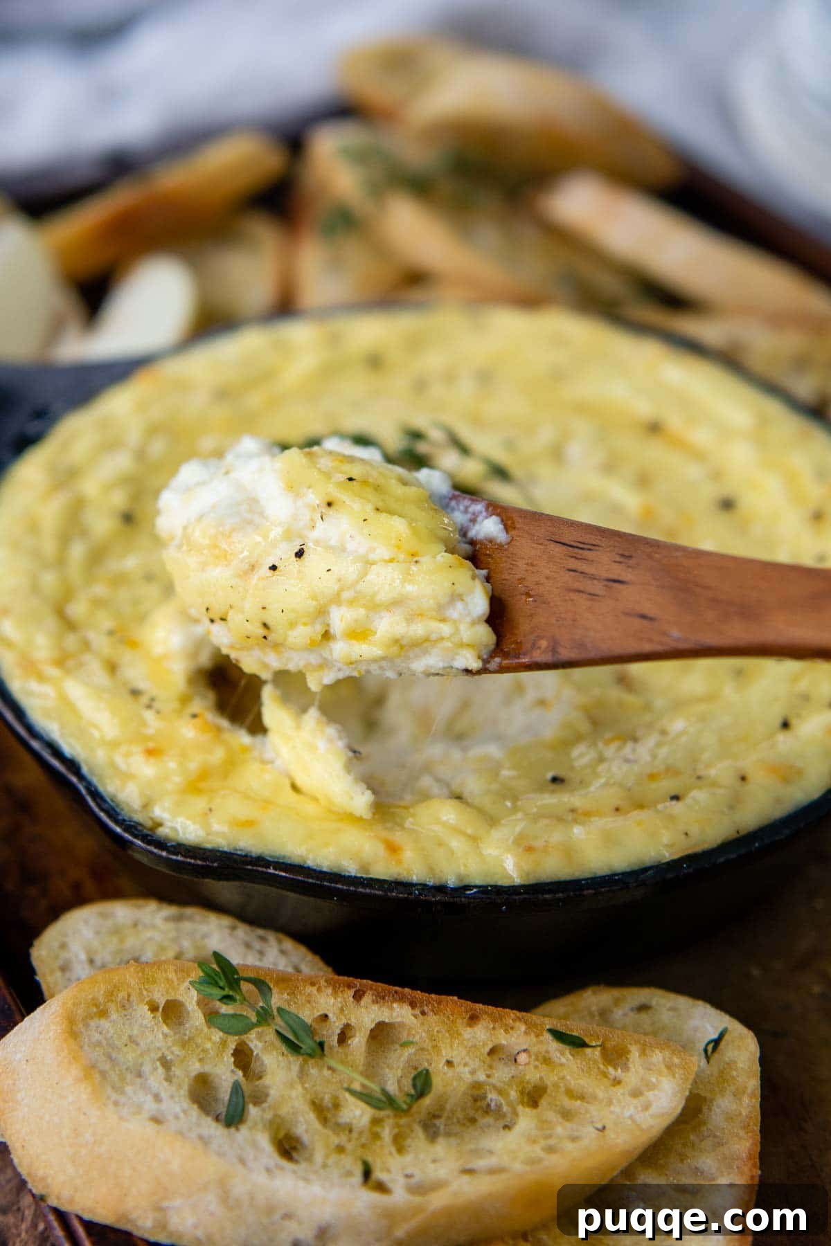 Honeyed Orange Ricotta Bake 3 A wooden spoon lifting a scoop of smooth, creamy ricotta dip from a bowl, highlighting its perfect texture.