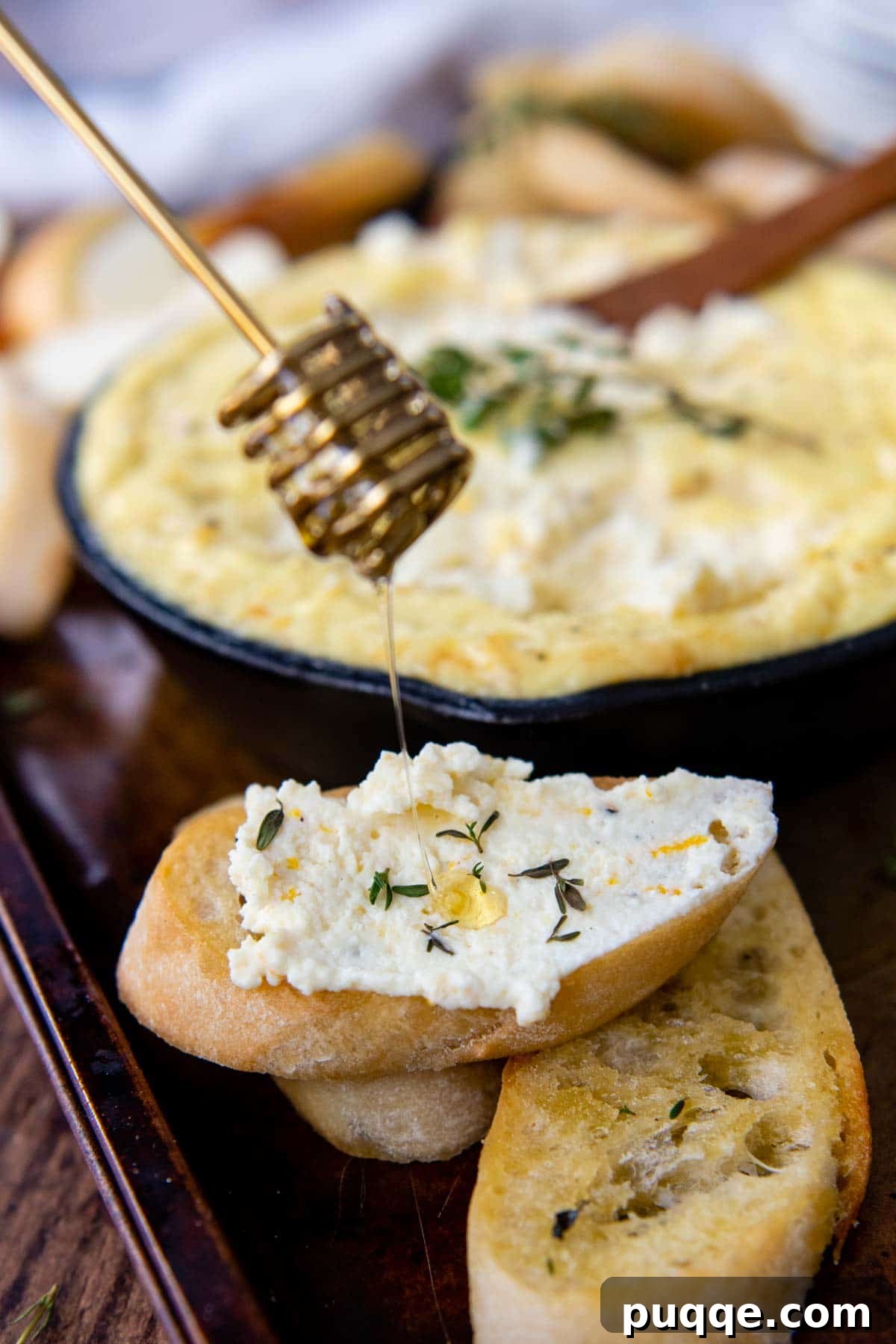 Honeyed Orange Ricotta Bake 5 A honey dipper drizzling golden honey over a slice of toast spread with creamy baked ricotta.