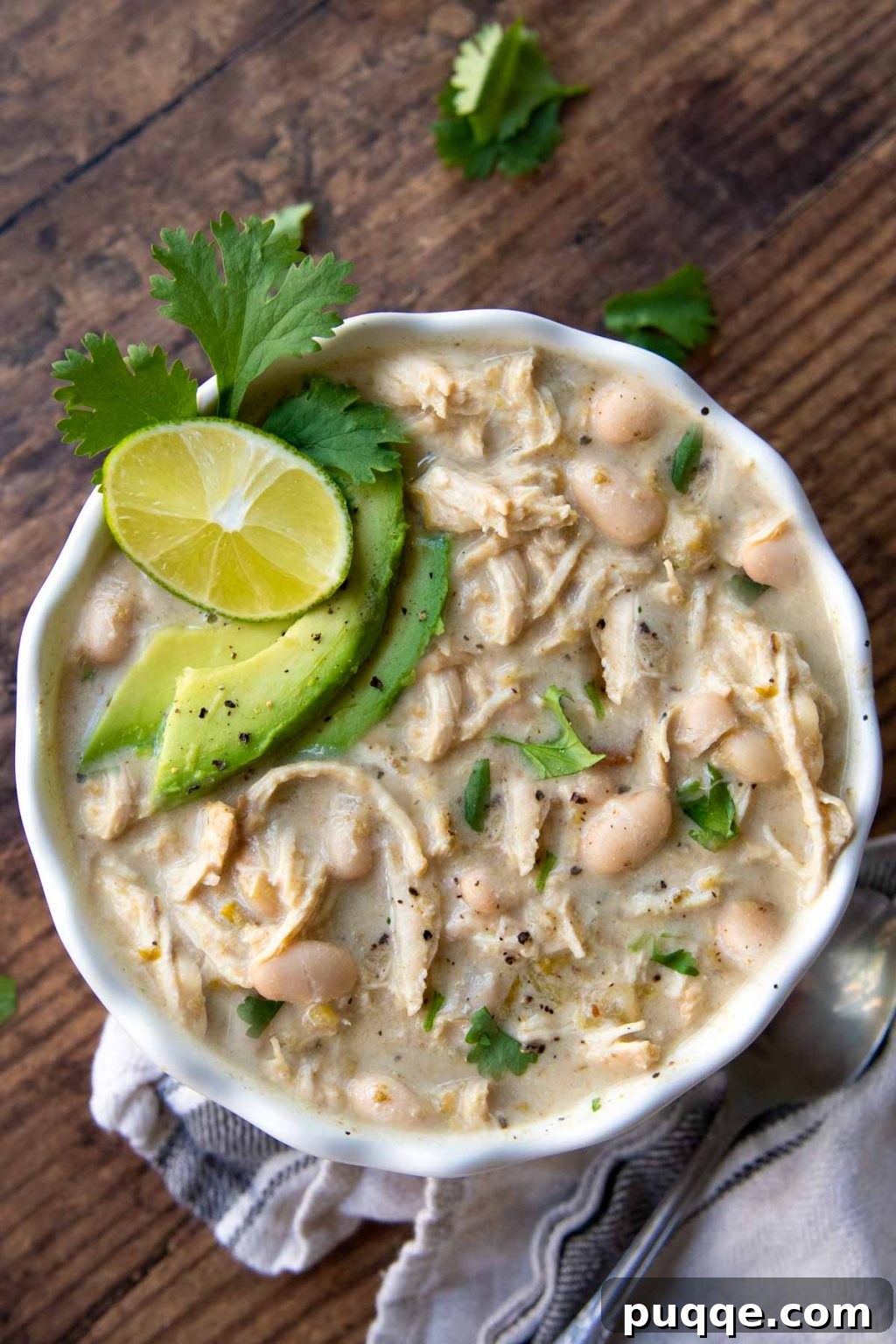 Gluten-Free White Chicken Chili The Secret to Its Deliciousness 2 Overhead shot of creamy Instant Pot White Chicken Chili garnished with sliced avocados, fresh cilantro, and a lime wedge.