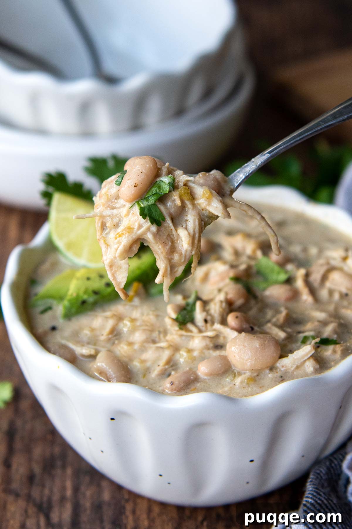 Gluten-Free White Chicken Chili The Secret to Its Deliciousness 6 A spoon lifting out a generous bite of creamy white chicken chili, showcasing its rich texture and ingredients.