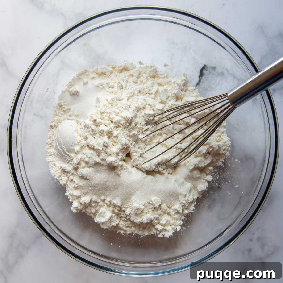 Sausage Cheddar Muffins 4 A large mixing bowl containing a whisk and the dry ingredients: flour, baking powder, and salt, ready to be combined.