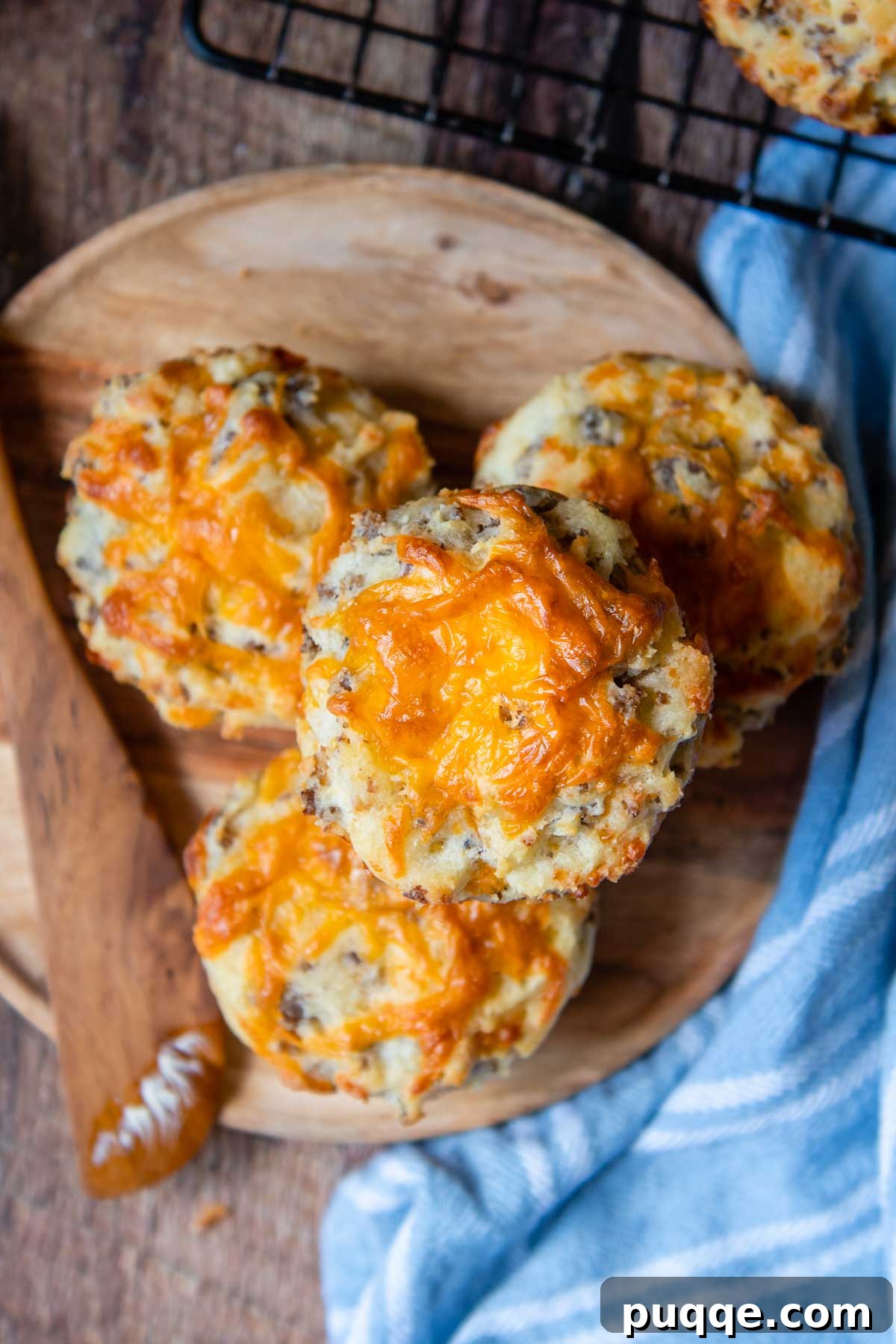 Sausage Cheddar Muffins 7 An overhead shot showcasing a batch of freshly baked sausage muffins with generous amounts of melted cheddar cheese on top, presented invitingly.