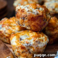 Sausage Cheddar Muffins 9 Two fluffy cheddar sausage muffins stacked on a small wooden plate.