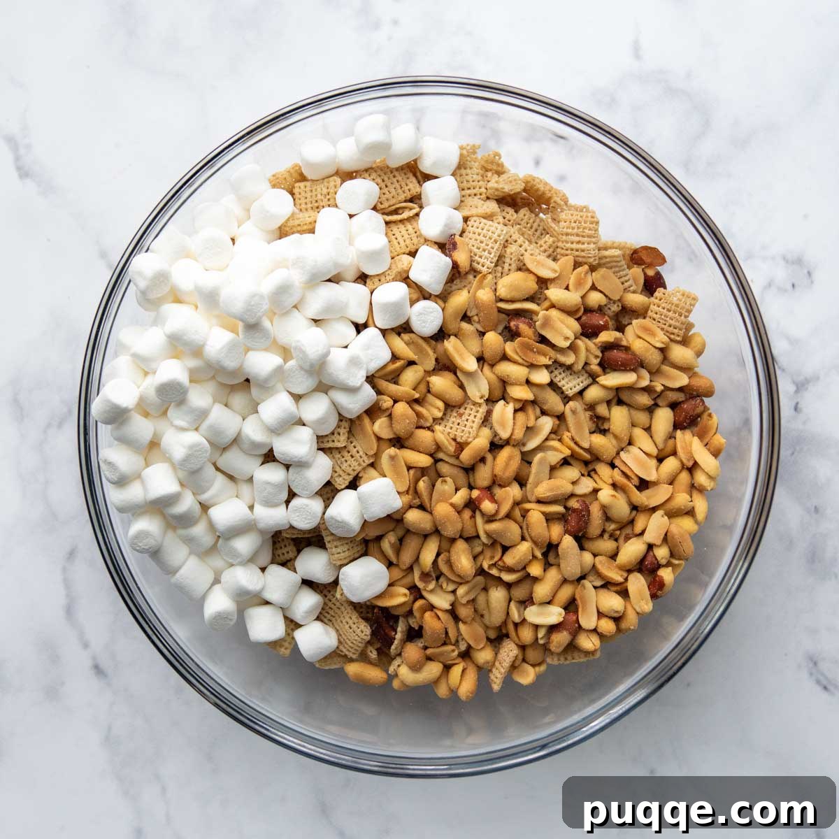 A large bowl containing the dry ingredients for Scotcheroos: Chex cereal, miniature marshmallows, and salted peanuts, perfectly mixed and ready for the wet ingredients.