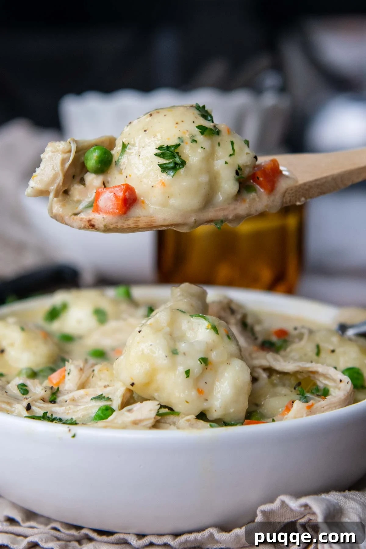 Speedy Gluten-Free Instant Pot Chicken and Dumplings 2 A wooden spoon holding up a scoop of thick, creamy Instant Pot gluten-free chicken and dumplings, showcasing tender chicken pieces and fluffy dumplings.