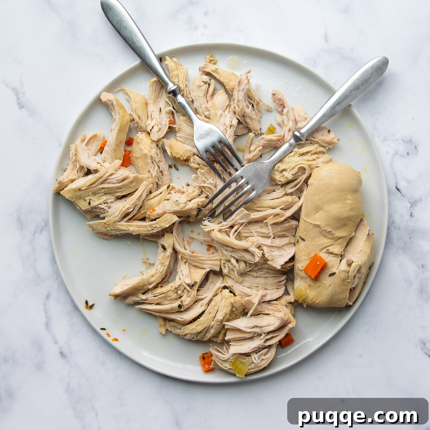 Speedy Gluten-Free Instant Pot Chicken and Dumplings 5 Cooked chicken breasts being shredded on a plate with two forks, ready to be added back into the soup.