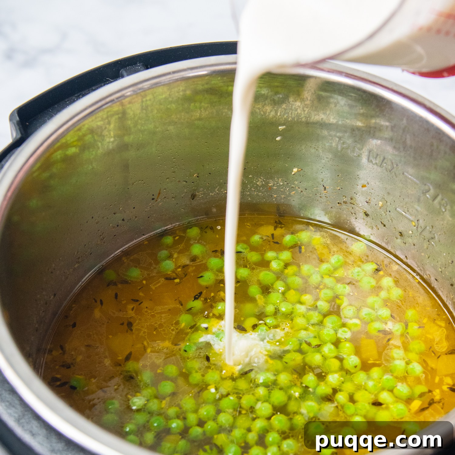 Speedy Gluten-Free Instant Pot Chicken and Dumplings 6 Heavy cream mixed with cornstarch being poured into the simmering chicken soup in an Instant Pot.