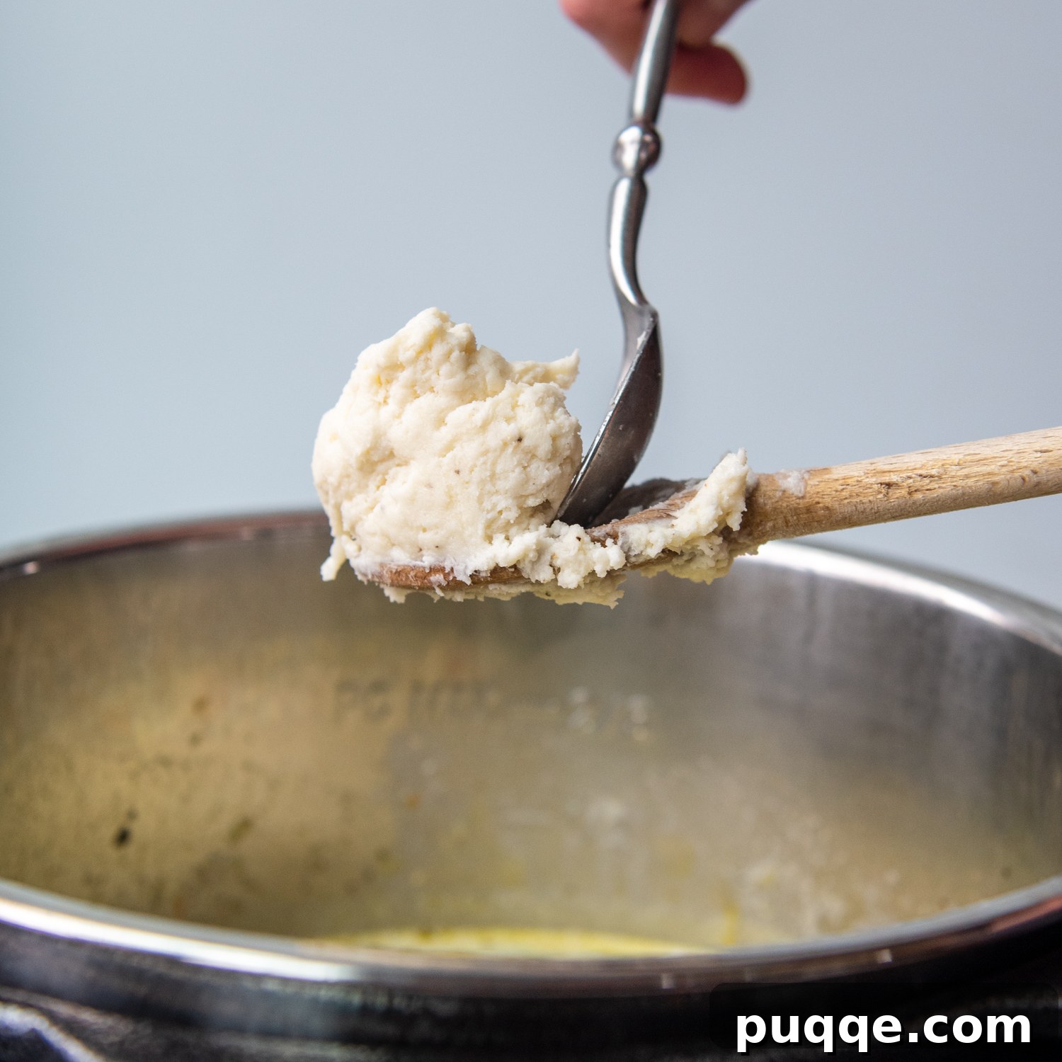 Speedy Gluten-Free Instant Pot Chicken and Dumplings 8 A spoon scraping dumpling dough into the simmering chicken soup in an Instant Pot, demonstrating the drop dumpling method.