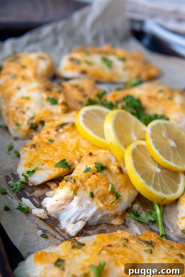 a broken up piece of parmesan crusted tilapia on a baking sheet, close up