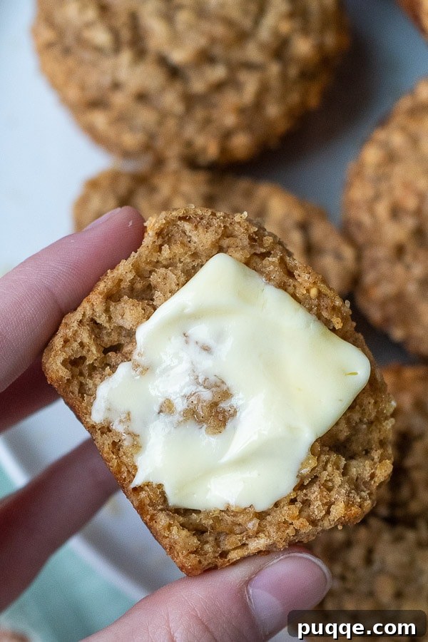 Wholesome Applesauce Oat Muffins 8 A sliced applesauce oatmeal muffin with a dollop of melted butter on top, showcasing its internal texture.