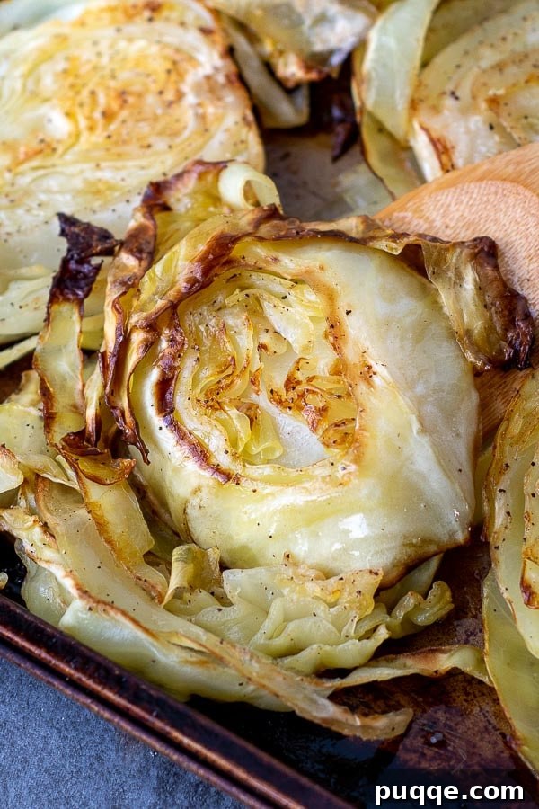 Golden Crispy Cabbage Steaks 6 A close-up view of a pan of oven roasted cabbage steaks, showcasing their rich golden color, crispy edges, and tender texture.