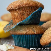 A stack of two beautifully baked gluten-free banana muffins, with one showing its fluffy interior and blue paper liner.