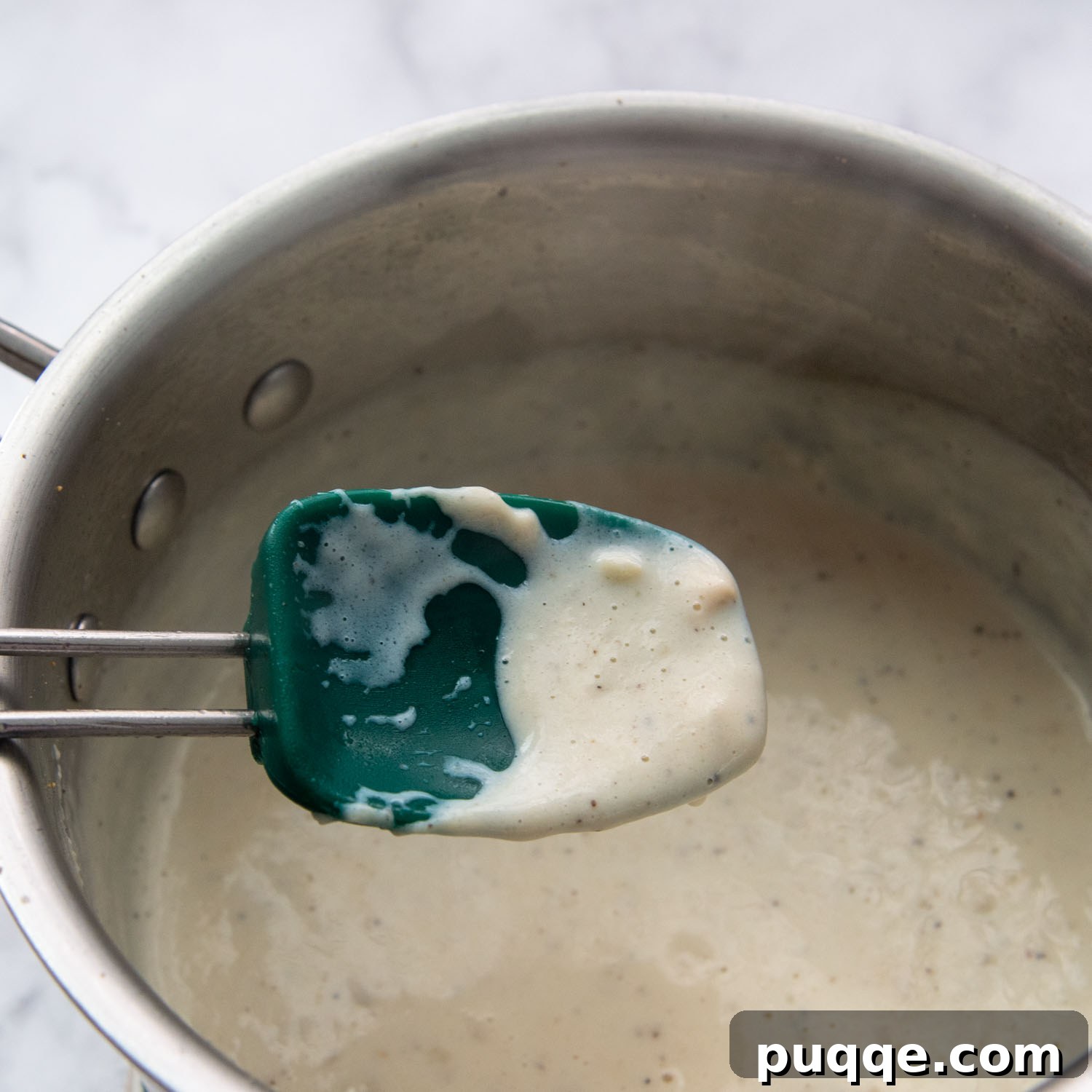 Velvety Fresh Spinach Artichoke Dip 5 A spoon lifting the thickened white sauce, demonstrating its rich, coats-the-back-of-a-spoon consistency.