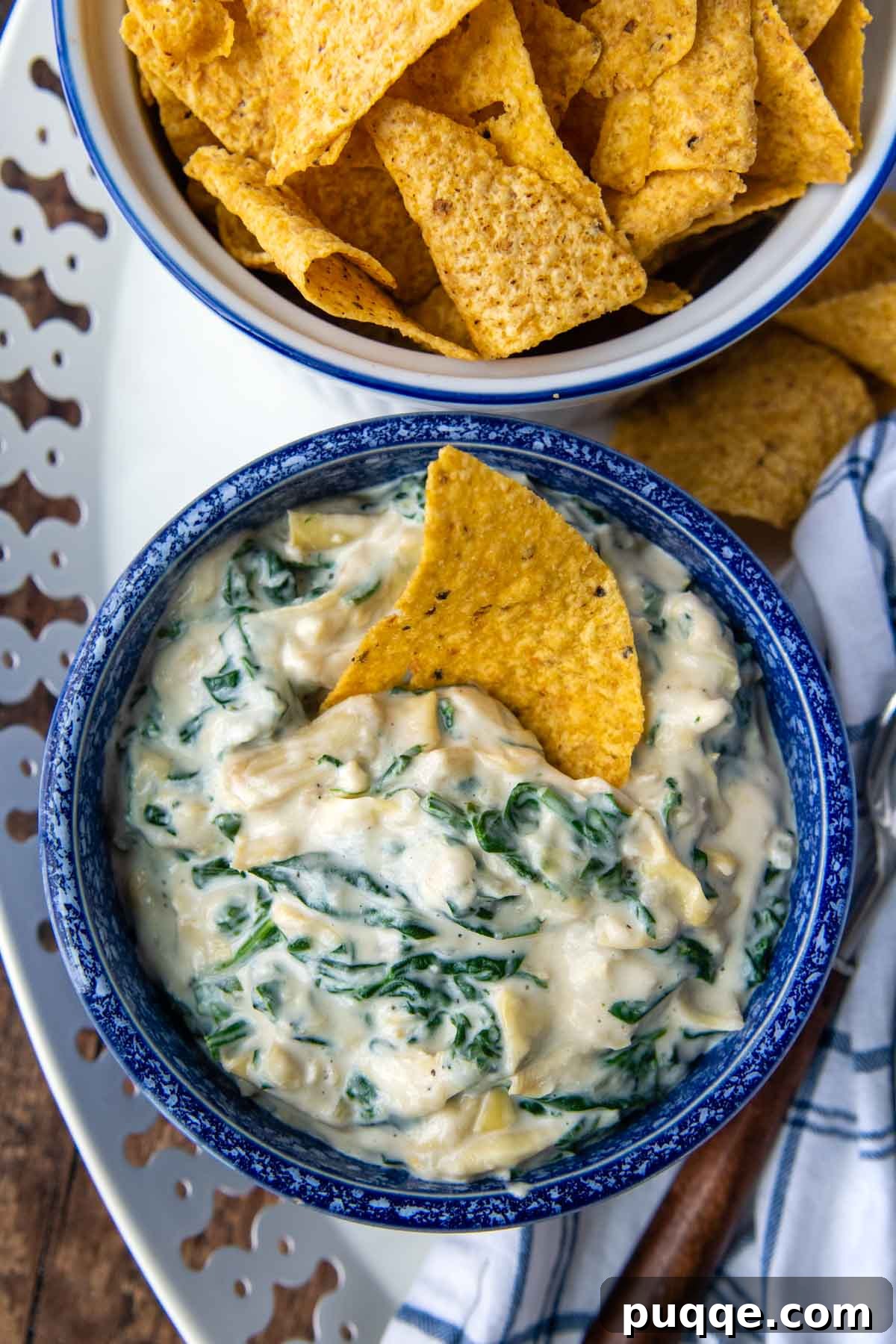 Velvety Fresh Spinach Artichoke Dip 8 An overhead shot of a vibrant blue bowl filled with warm, inviting spinach artichoke dip, garnished and ready to serve.