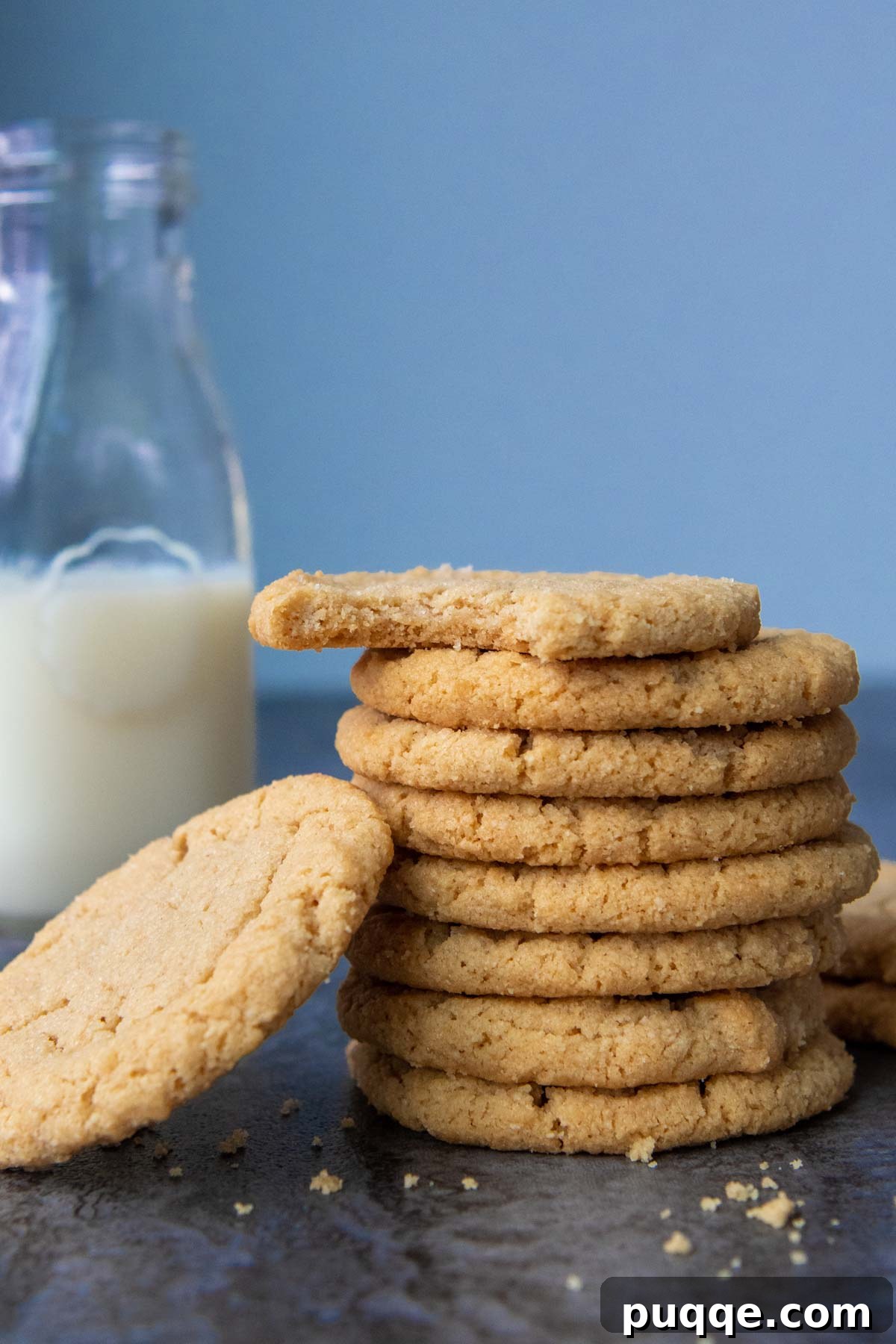 A stack of golden-brown almond flour peanut butter cookies, perfectly baked and chewy, positioned next to a refreshing glass of milk, inviting a classic snack experience.