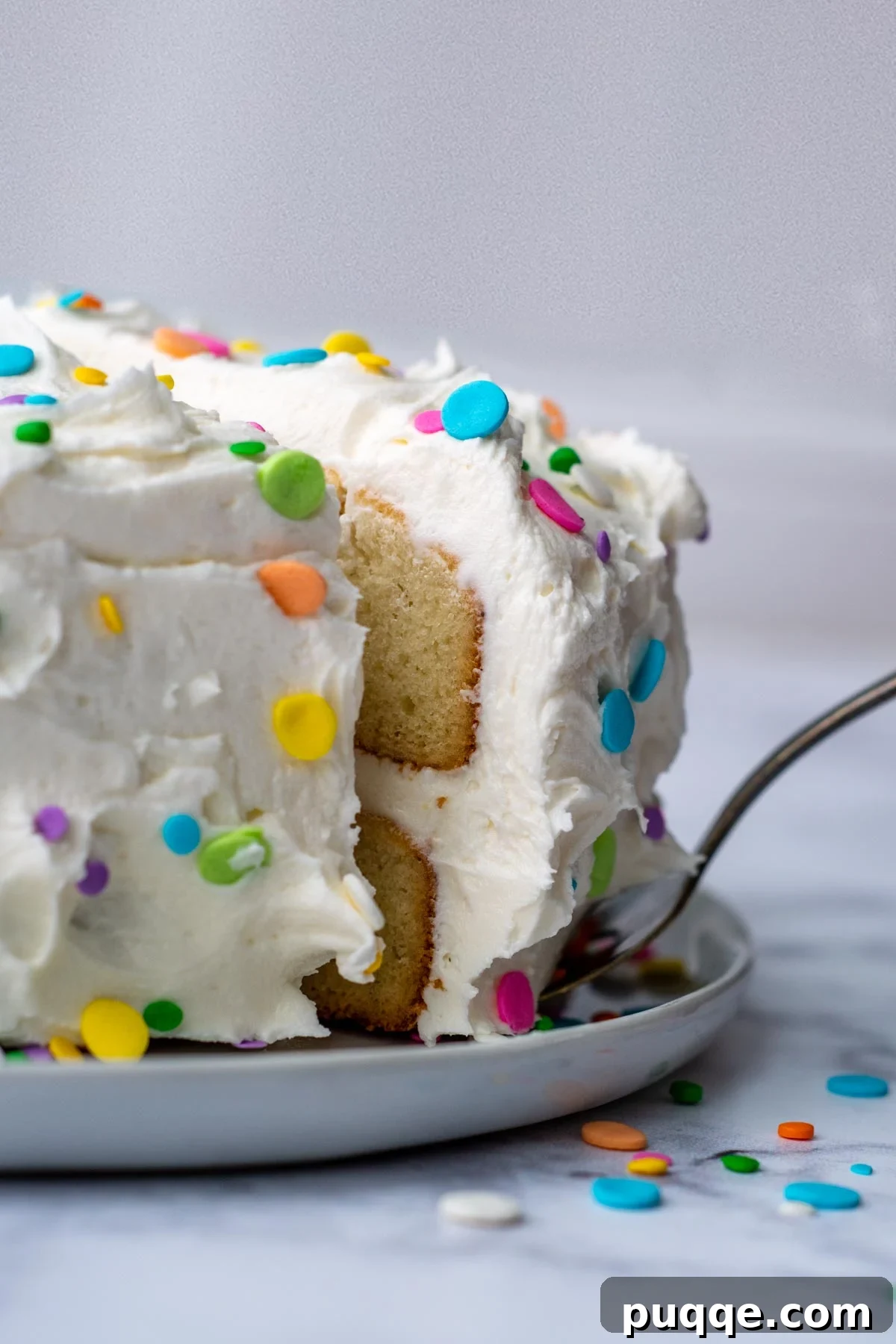 A delectable slice of fluffy and moist gluten-free white cake being served from a platter, ready to be enjoyed.