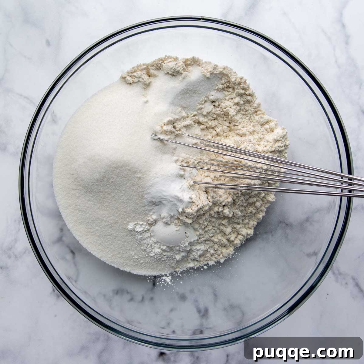 Dry ingredients for the gluten-free white cake, including flour, sugar, baking powder, baking soda, and salt, mixed in a glass bowl.