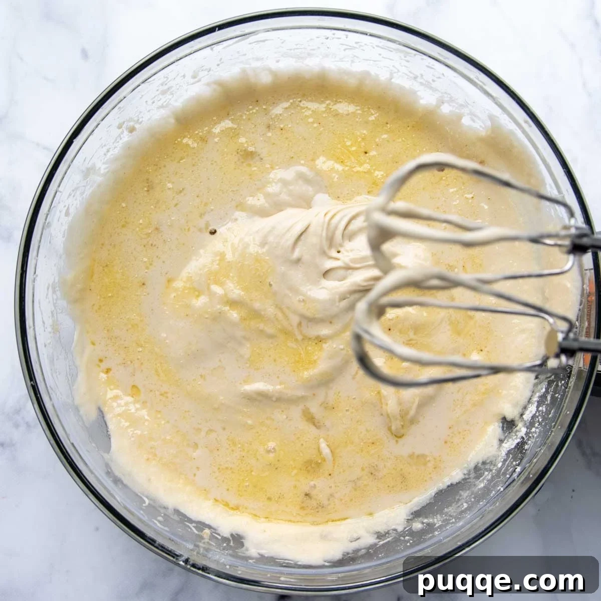 Gluten-free cake batter being mixed in a stand mixer, showing its pale and fluffy texture before baking.