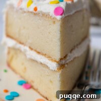 A slice of fluffy, moist gluten-free white cake, showcasing its delicate texture and perfect frosting.