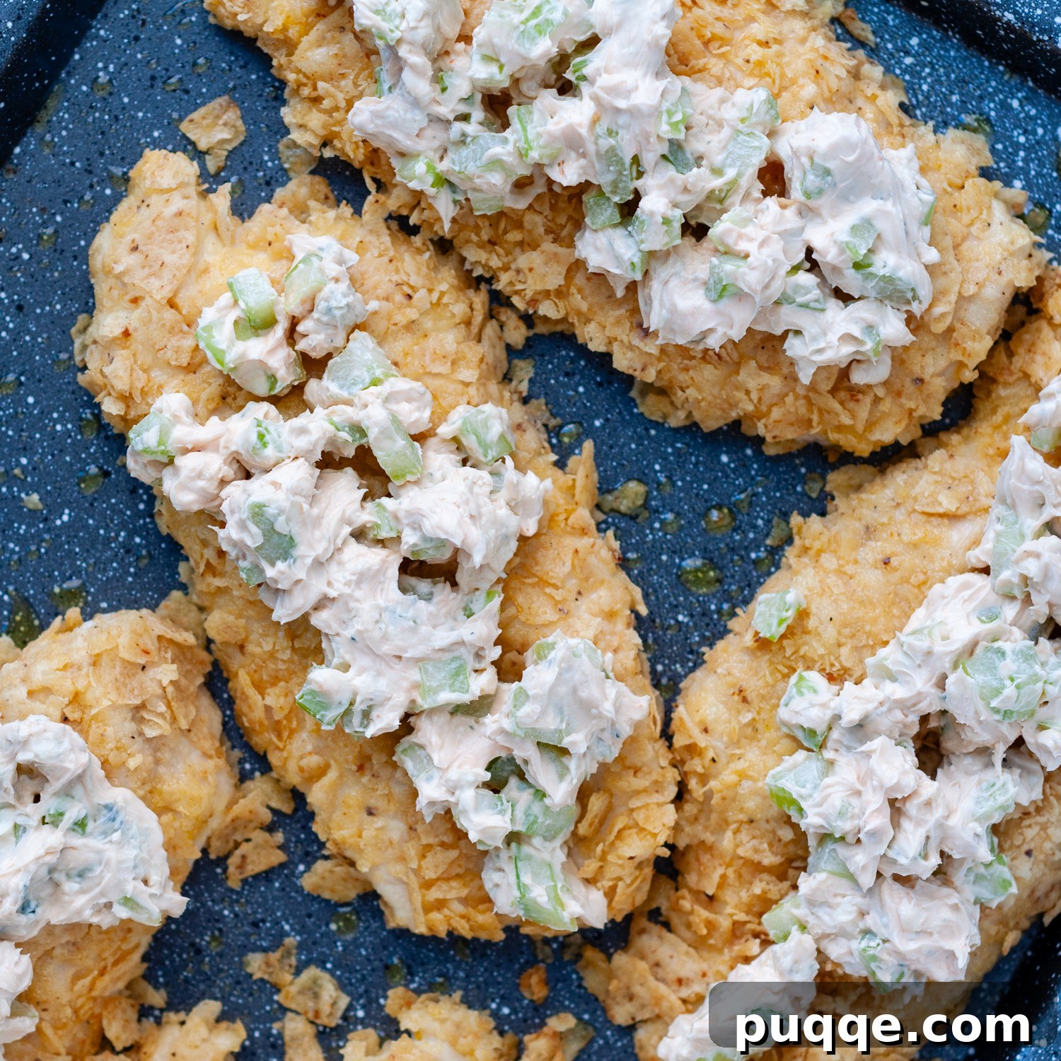 Cream cheese buffalo topping being spread over baked tortilla crusted chicken.