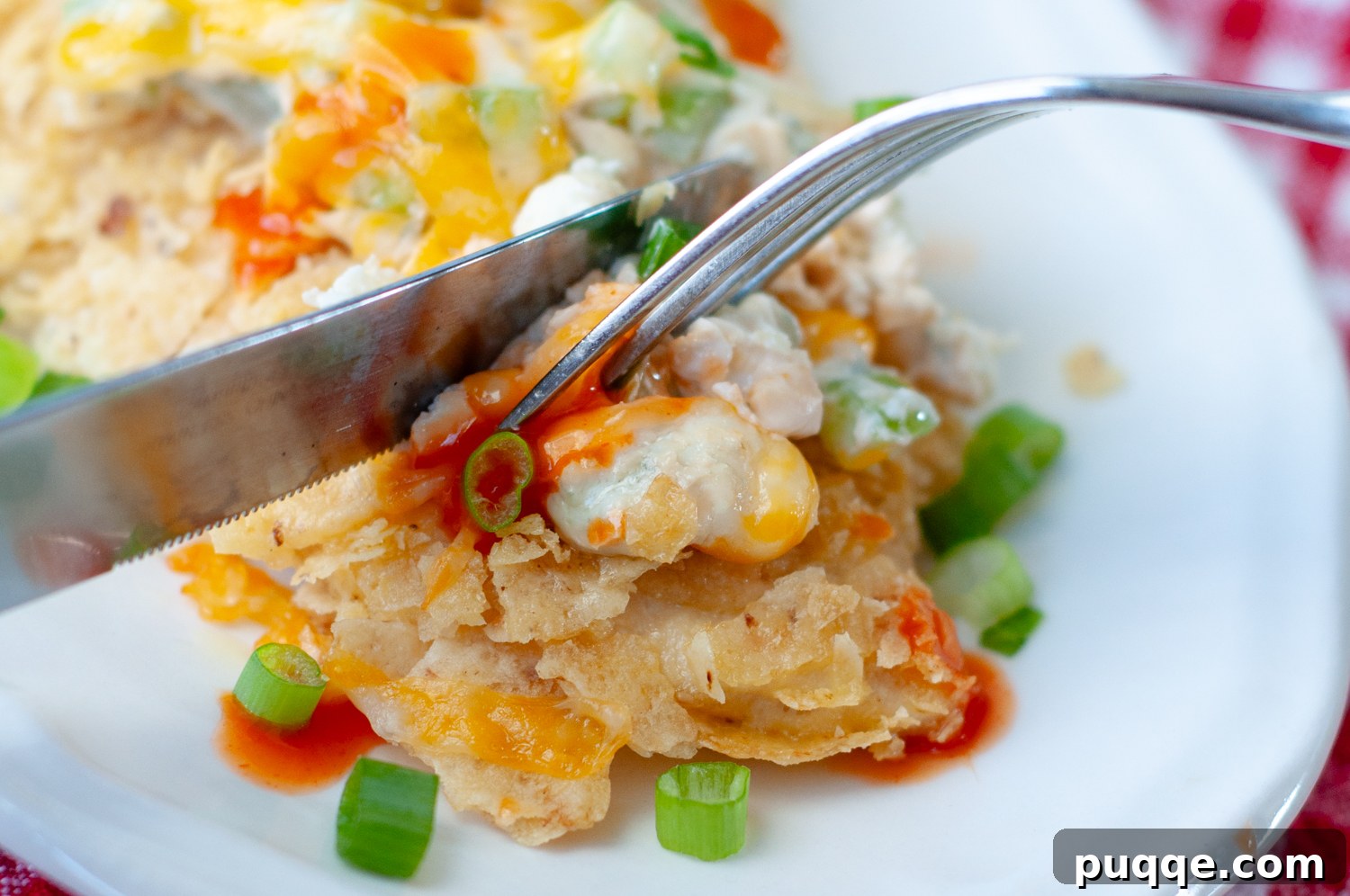A fork cutting into a piece of crispy tortilla crusted buffalo chicken, showing the tender interior.