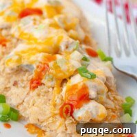 Baked buffalo chicken on a white plate with a fork resting nearby
