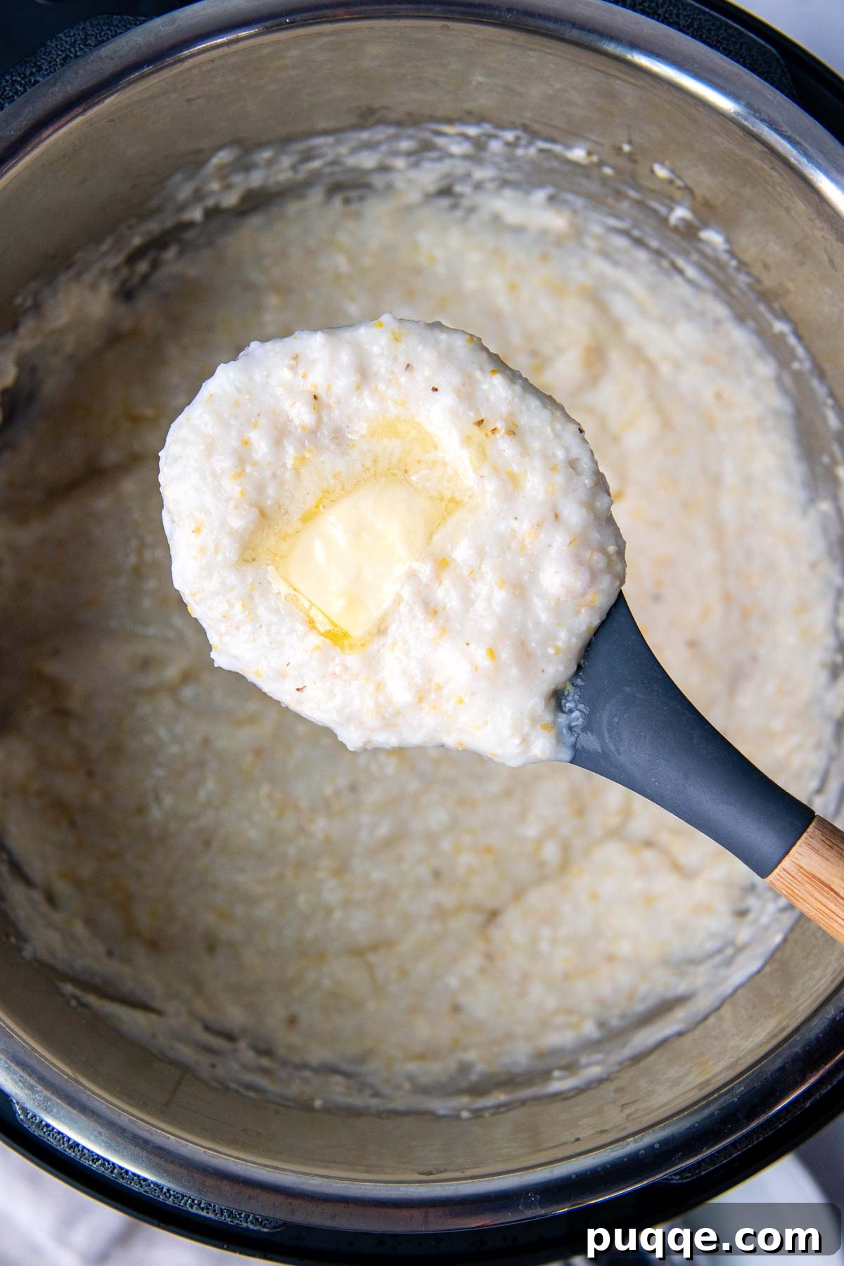 A scoop of grits with melted butter on top being held up from an Instant Pot, showcasing its creamy texture.