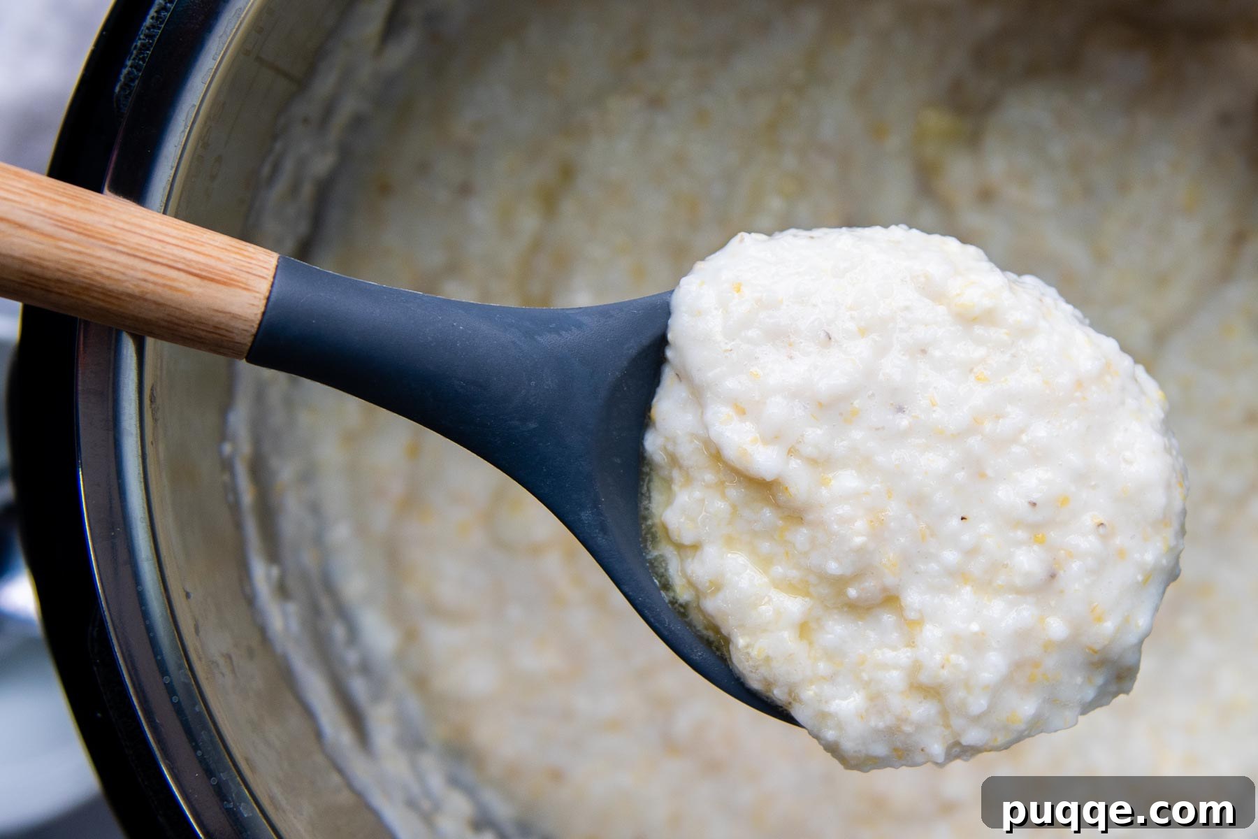 A ladle holding up creamy, perfectly cooked grits from an Instant Pot, ready to be served.