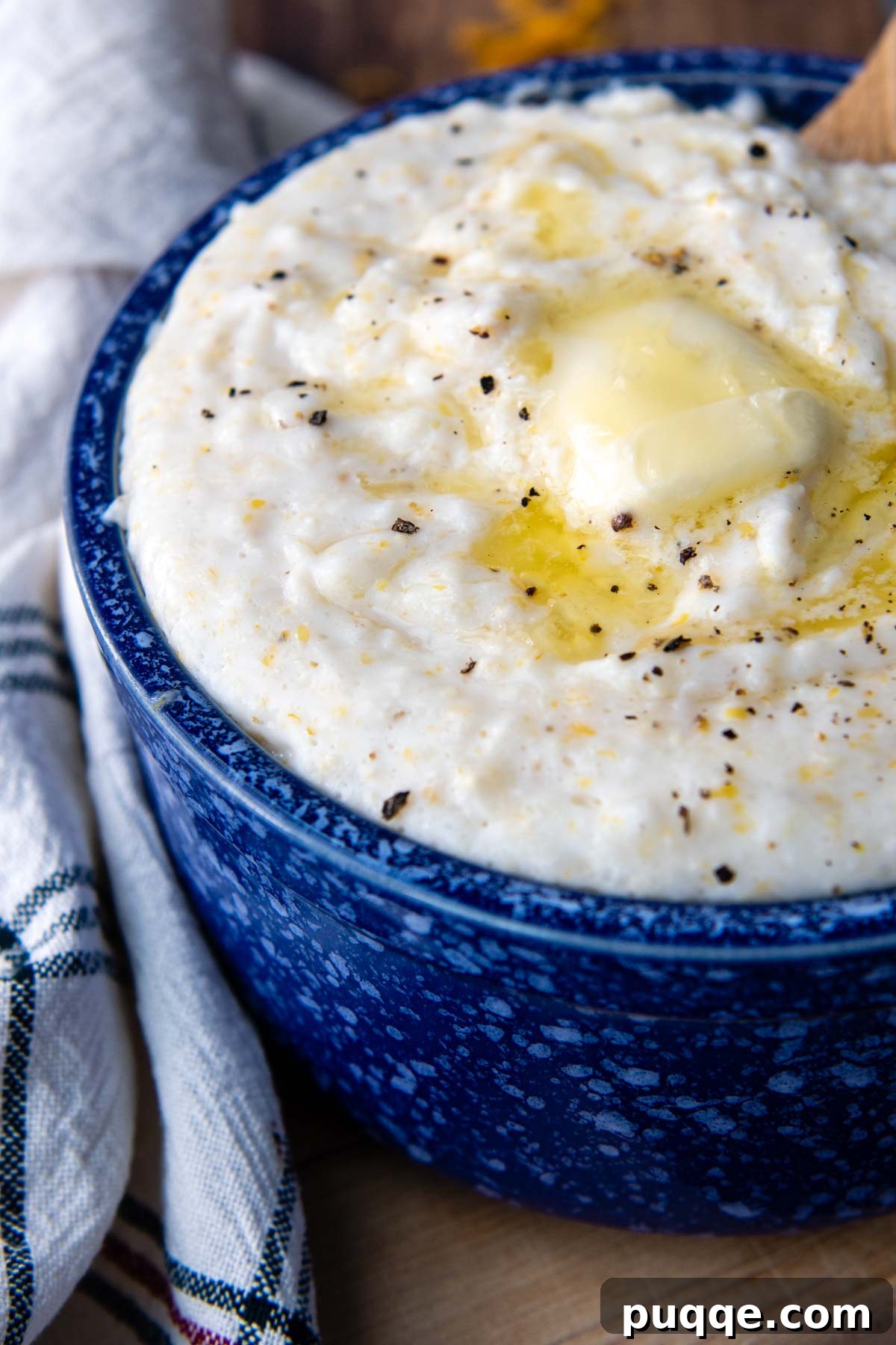 A beautifully presented bowl of creamy grits, adorned with melted butter and cracked black pepper.