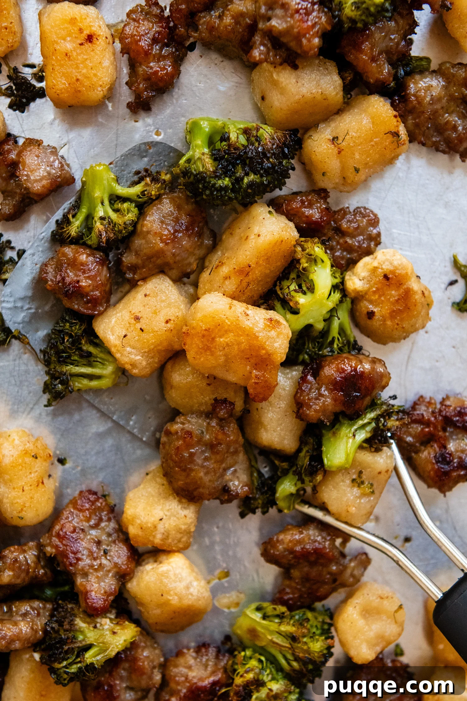 Roasted Gnocchi Sausage & Broccoli Sheet Pan Supper 2 Close up of cooked gnocchi, broccoli and sausage on a metal spatula.