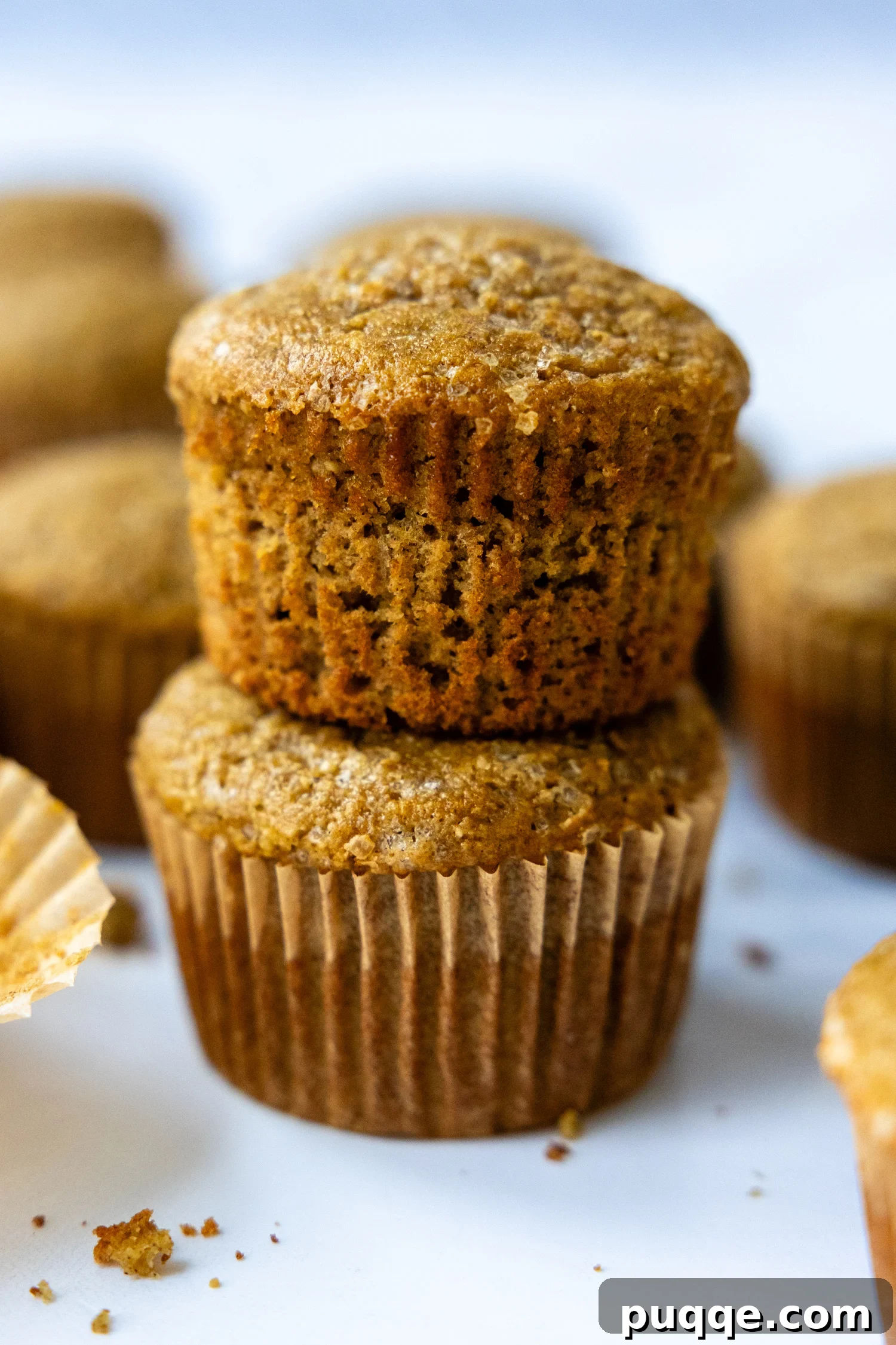 Pillowy Soft Gluten Free Oat Flour Banana Muffins 7 Two perfectly baked banana oat muffins stacked on top of each other, showcasing their tall, fluffy domes.