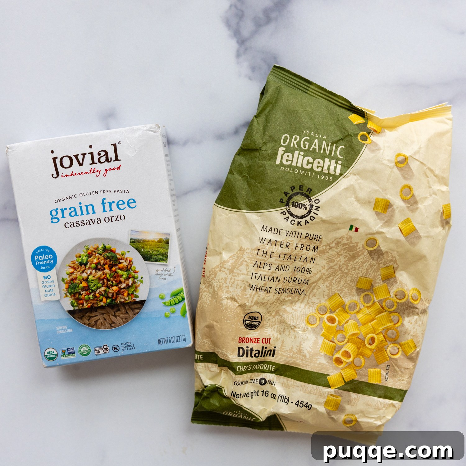 Various types of small pasta, including gluten-free ditalini and orzo, laid out on a surface.