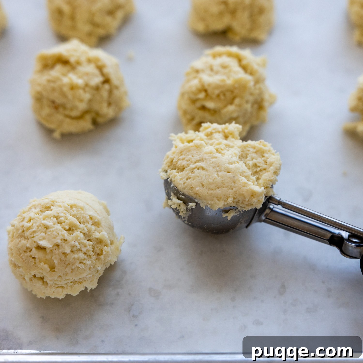 Cozy Gluten-Free Chicken and Biscuits 4 Gluten-free biscuit dough being scooped and dropped onto parchment paper for partial baking.