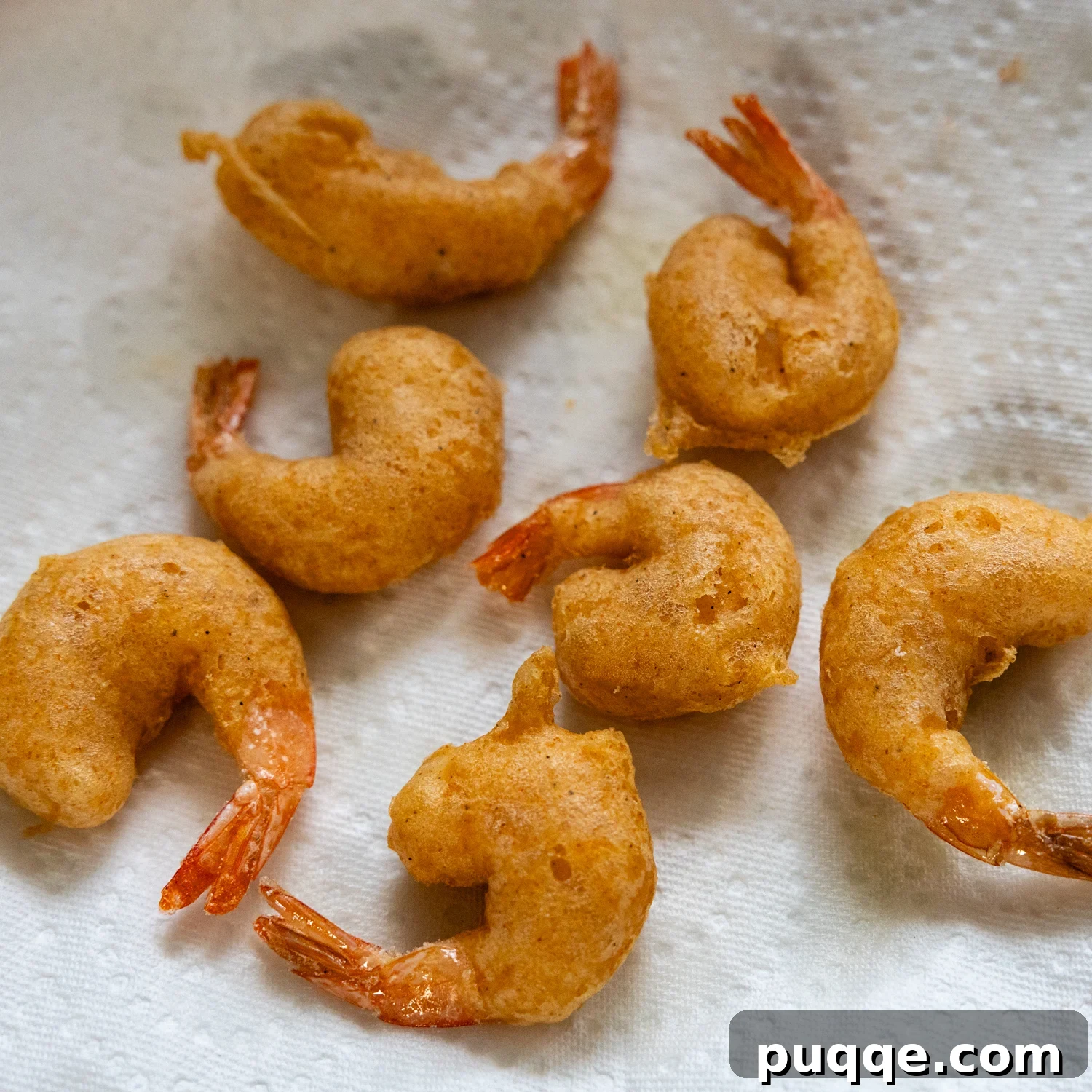 Golden Crispy Gluten-Free Shrimp 8 A batch of golden-brown, crispy fried shrimp resting on a paper towel-lined plate after frying.