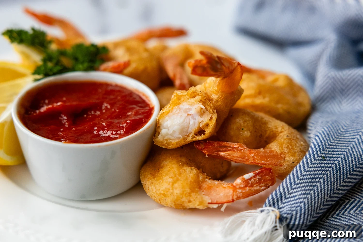 Golden Crispy Gluten-Free Shrimp 10 A vertical close-up image showing the inside of a piece of crispy battered shrimp, revealing the tender shrimp and light coating.