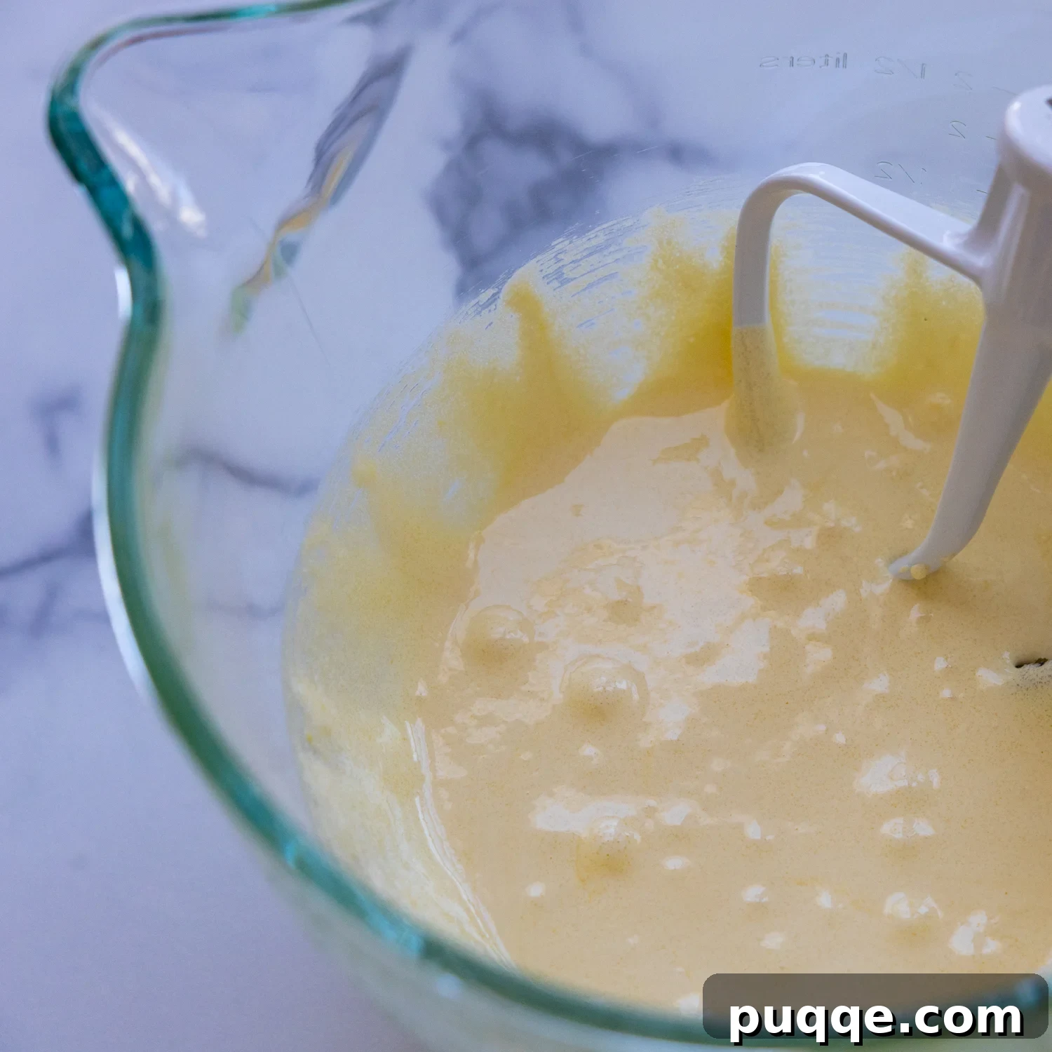 Absolutely Perfect Gluten-Free Tres Leches Cake 4 Egg yolk and sugar being mixed in a glass bowl, showcasing the pale yellow and voluminous texture.