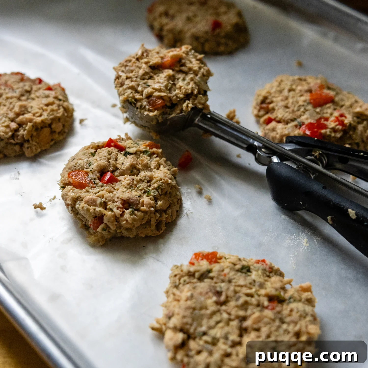 Golden Brown Flourless Salmon Patties 5 Scoop placing uncooked patties on parchment paper.