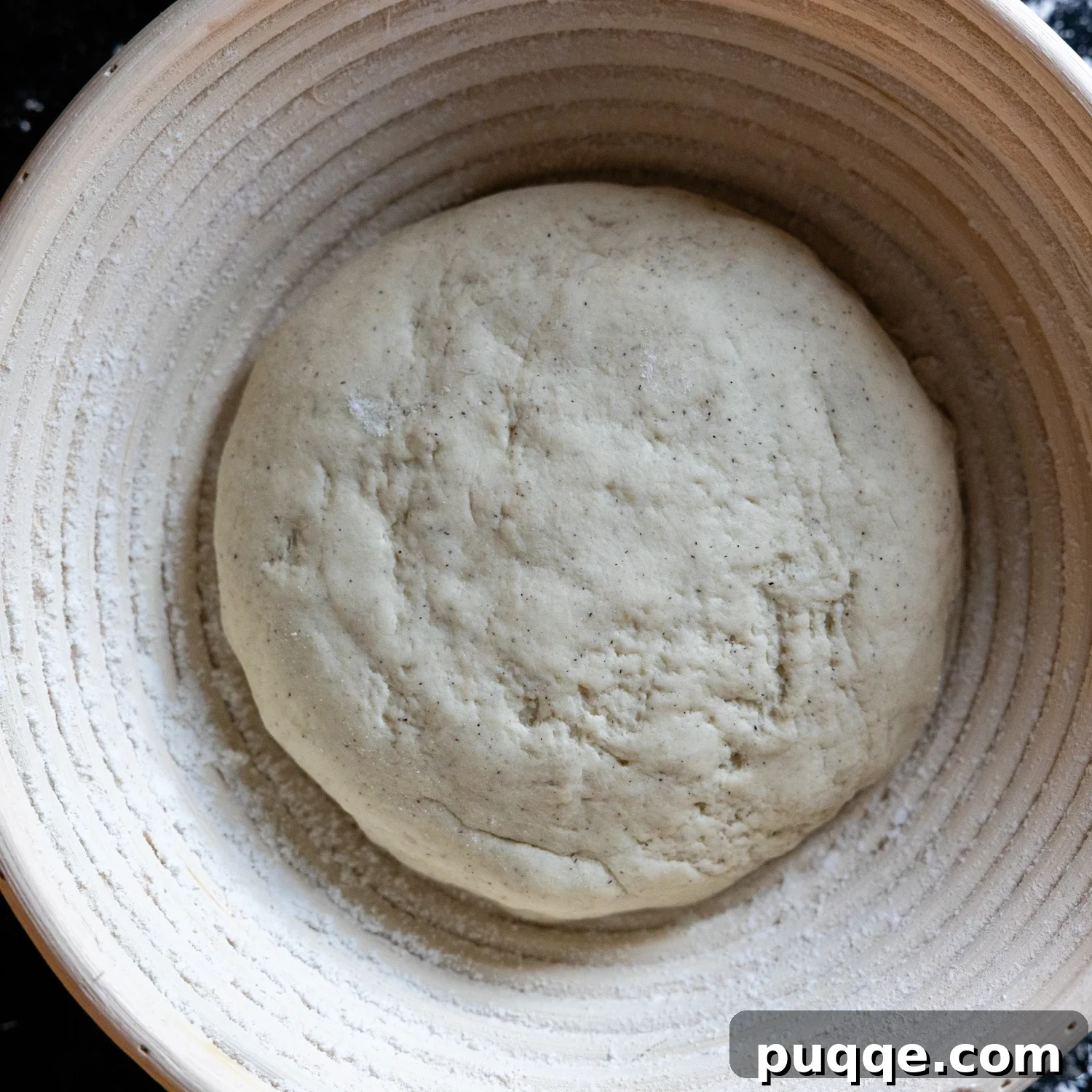Uncooked, unbaked gluten-free sourdough loaf resting in a floured proofing basket (banneton).