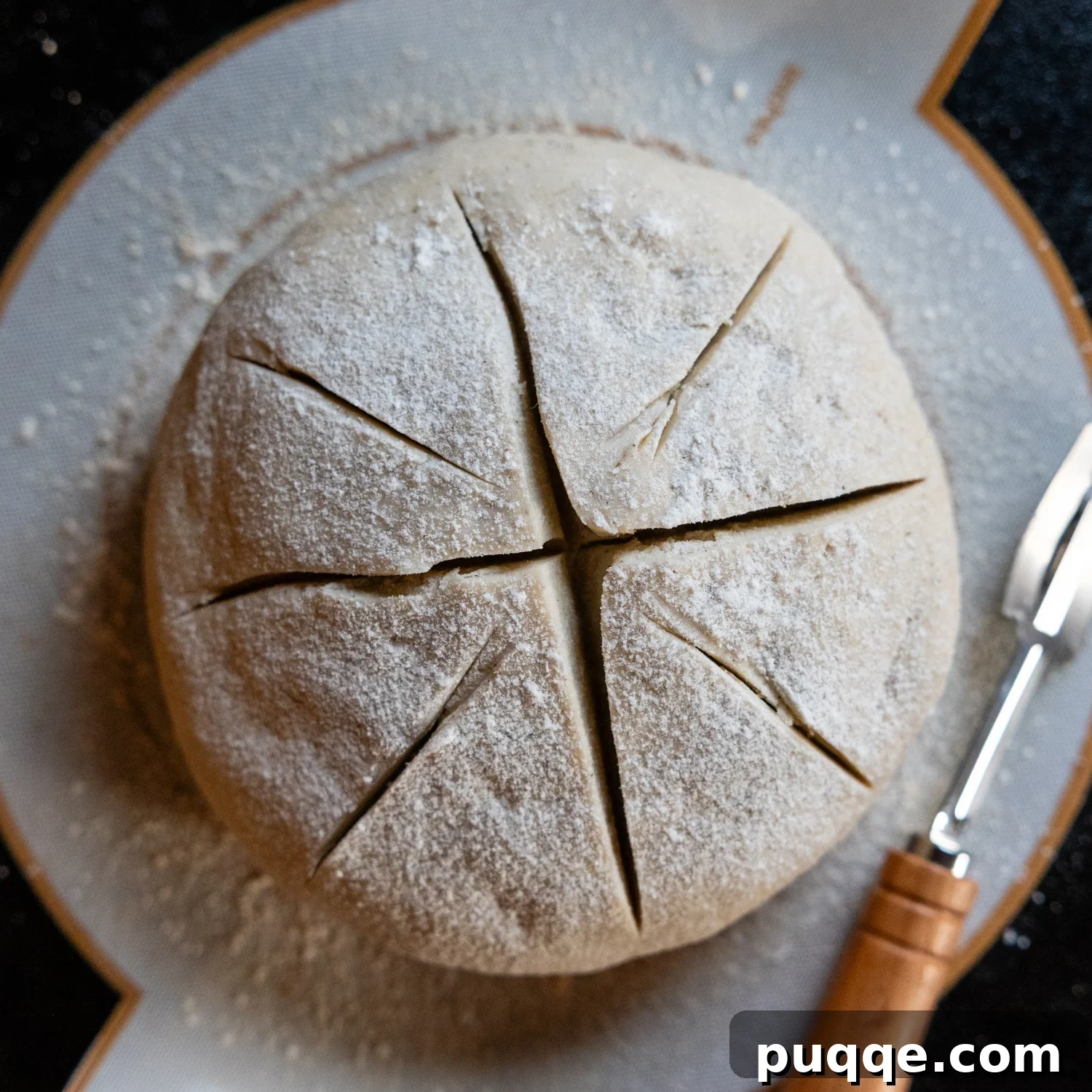 Overhead view of a deeply scored, uncooked gluten-free sourdough loaf, ready for baking.