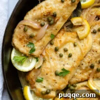 Gluten Free Chicken Piccata in a skillet with lemon garnish and topped with capers.